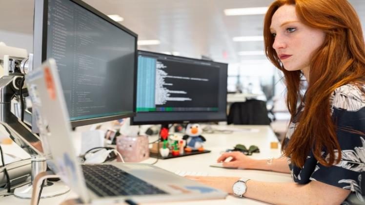 A woman in an office researching organizational knowledge on her computer